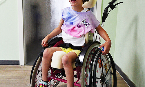 Kind sitzt entspannt in einem therapeutischen Reha-Sitz im Innenraum